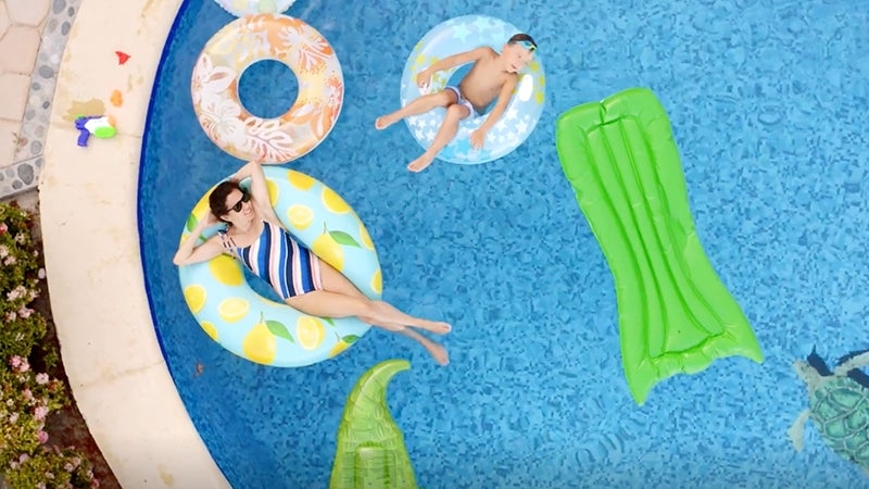 Woman and child relaxing with inflatable water toys in a swimming pool