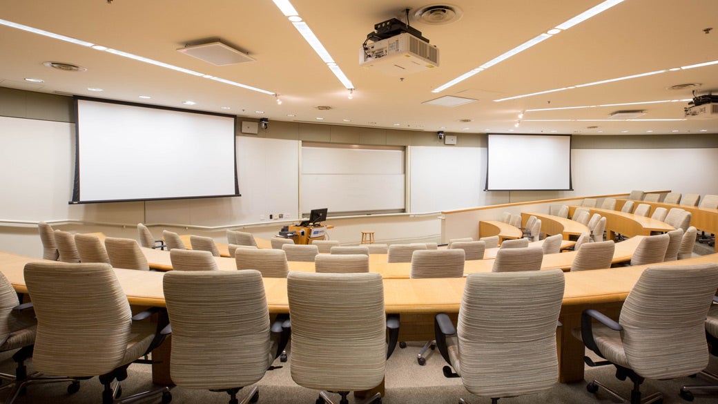 An empty large classroom space at UCLA Anderson with semi-circle tables