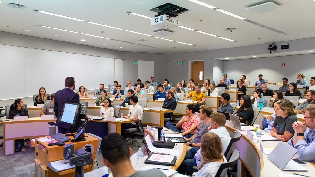 Students in class lecture with open laptops in a large classroom space at UCLA Anderson