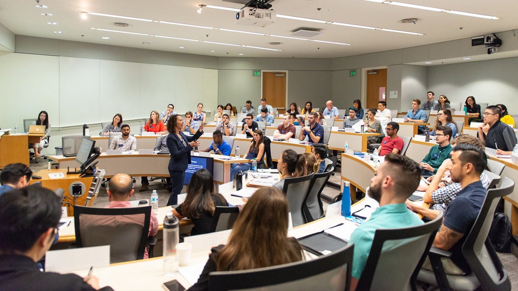 Students listening to a faculty member in a large classroom space at UCLA Anderson