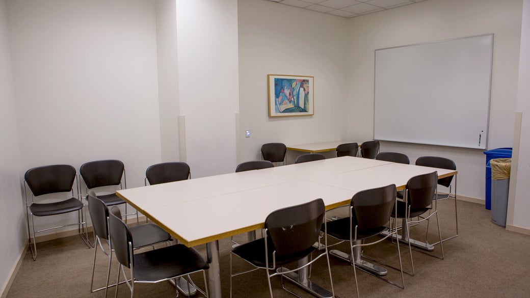 Empty seminar room 1 at UCLA Anderson with square tables, movable chairs and mounted whiteboard