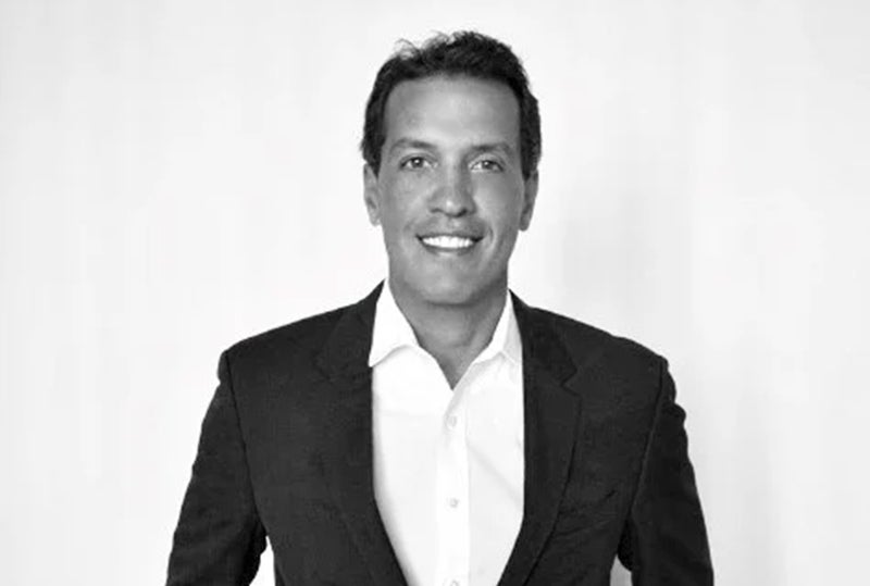 black and white portrait of alex nascimento in dark suit and white shirt with no tie
