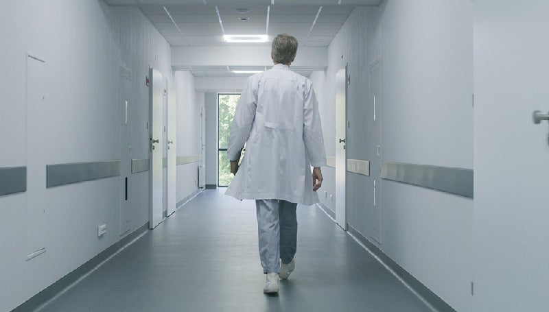 A doctor in a white coat walking down a hospital hallway